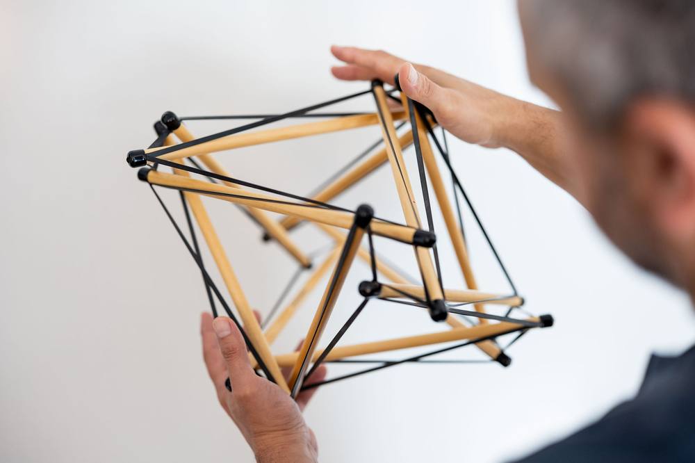 Dean Haspey holding a tensegrity model, a structure held in shape by the balance of tension across the whole system